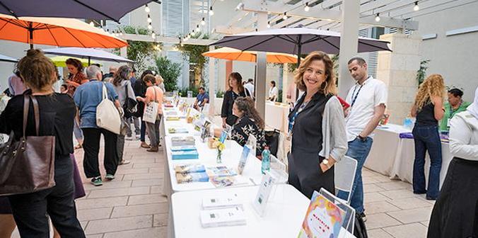 Woman displaying books in the courtyard of Mandel Foundation building